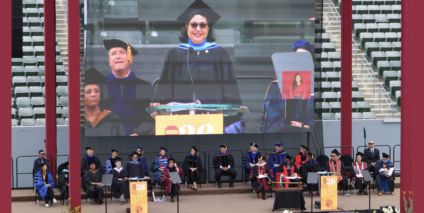 A stage filled with commencement ceremony speakers wearing ceremonial robes.